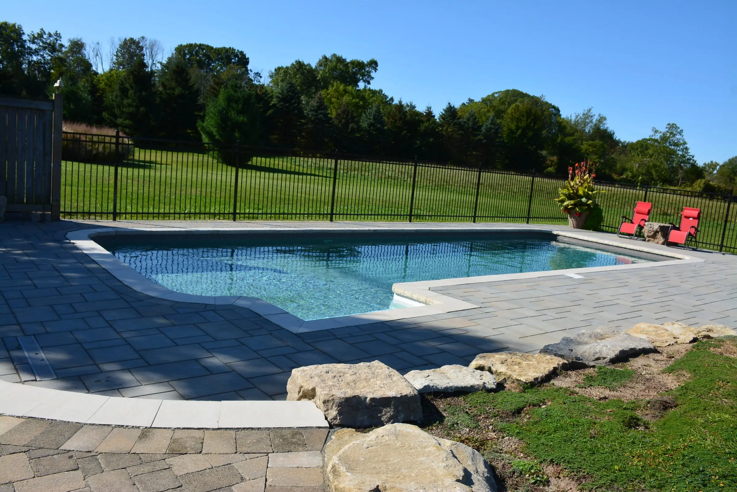 Inground pool with paver patio and armour stone